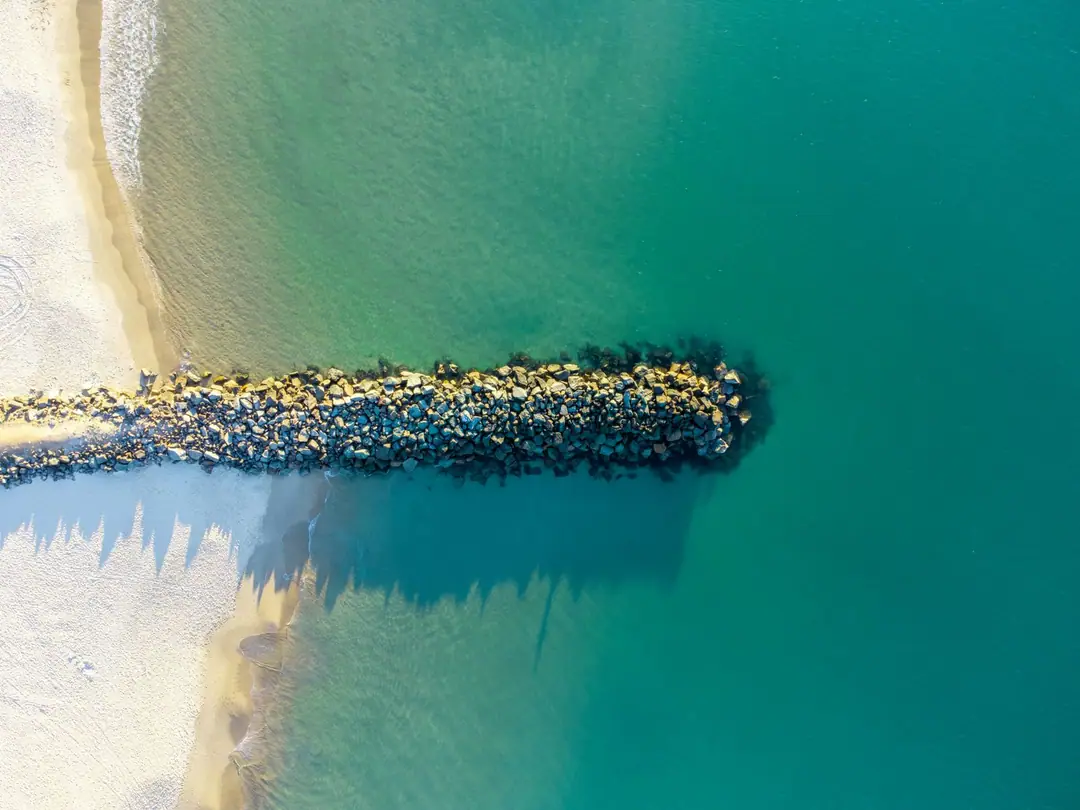 A stunning aerial shot of a rock jetty and beach at Noosa Heads, Queensland, Australia.